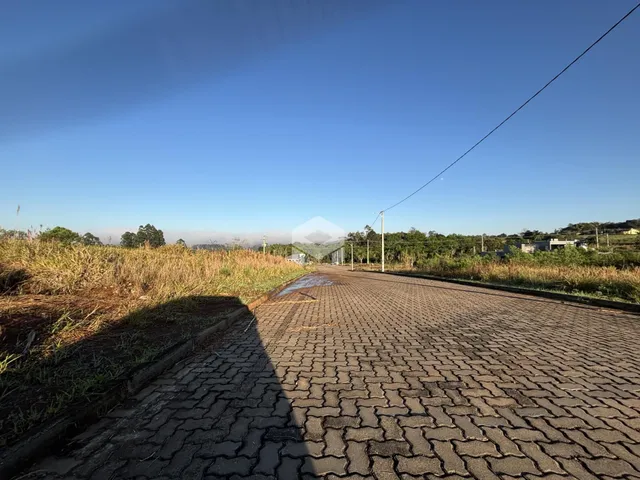 Uma estrada pavimentada atravessa uma área de campo gramado sob um céu azul.