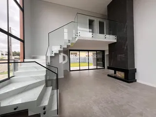 Interior moderno com escadaria de vidro e detalhes em mármore escuro.