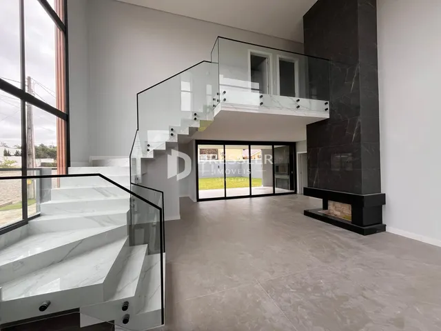 Interior moderno com escadaria de vidro e detalhes em mármore escuro.