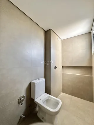 Foto de um banheiro com revestimento cerâmico e vaso sanitário branco.