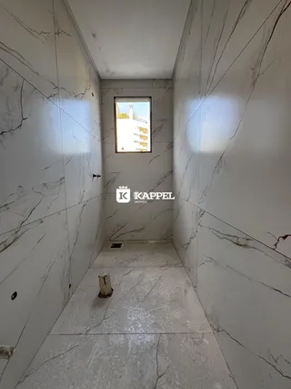 Corredor longo com paredes de mármore claro.