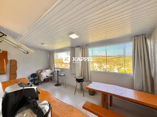 Vista interna de uma sala com piso de madeira e vista para a paisagem externa.