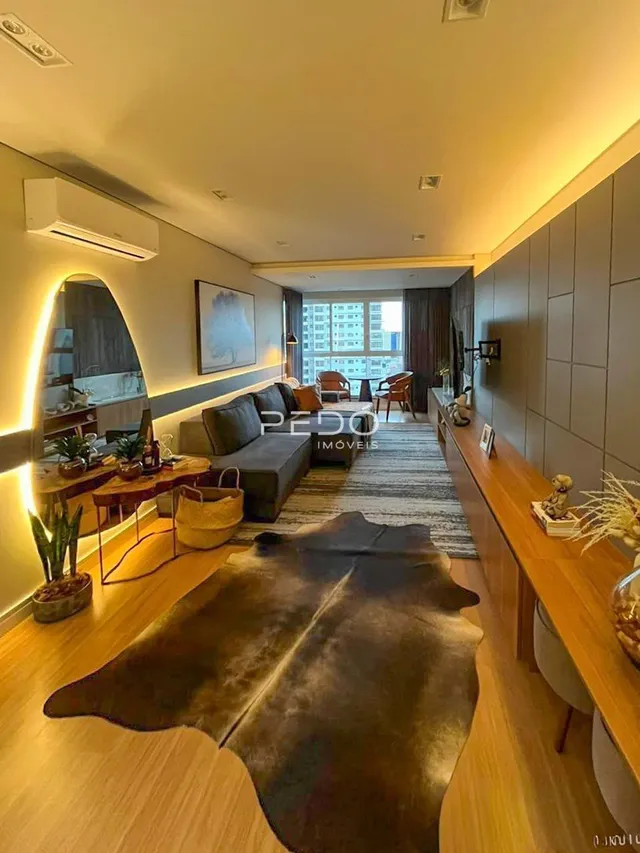 Sala de estar com piso de madeira e tapete na residência.