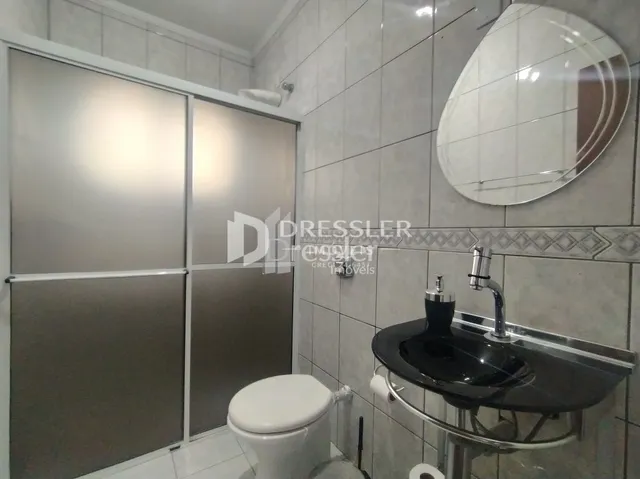 Foto de um banheiro com revestimento de azulejos brancos.