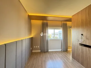 Sala de estar com piso de madeira e cortinas claras.