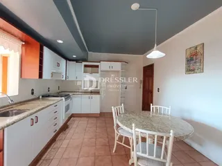 Foto de uma cozinha com armários brancos e mesa de jantar.