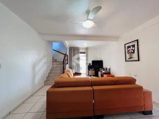 Sala de estar com sofá marrom e escadaria