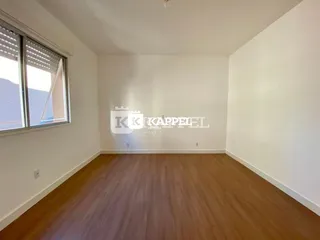 Uma sala de estar ampla com piso de madeira e paredes brancas.