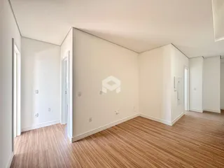 Interior de uma sala de estar com piso de madeira clara e paredes brancas.