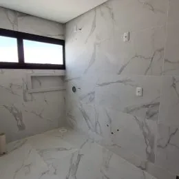 Parede e piso com acabamento em mármore claro em um imóvel.