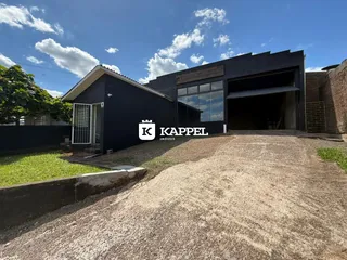 Fachada externa de uma residência escura com garagem aberta sob um céu azul.