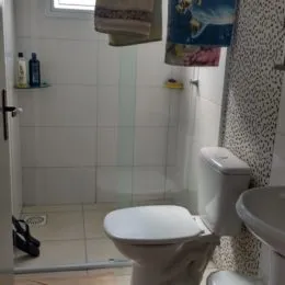 Foto interna de um banheiro com revestimento de azulejos brancos.