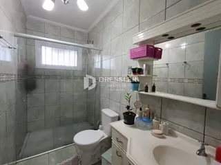 Foto de um banheiro com revestimento de azulejos cinzas e louças brancas.