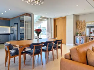 Uma sala de jantar ampla com mesa de madeira e cozinha moderna.