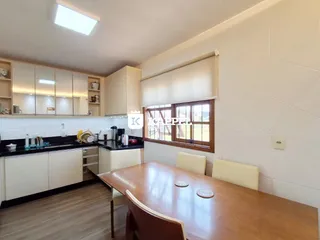 Foto de uma sala de jantar com mesa de madeira e armários brancos.