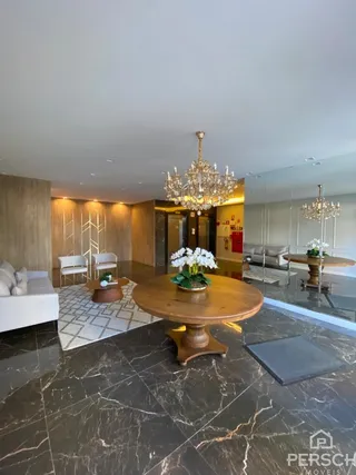 Sala de jantar ampla com piso de mármore escuro e mesa de madeira central.