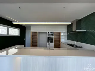 Cozinha moderna com armários brancos e bancada clara.