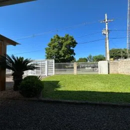Vista externa mostrando um gramado verde e árvores em uma propriedade.