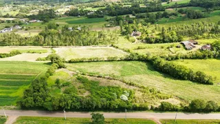 Vista aérea de uma paisagem rural com campos verdes e vegetação densa.