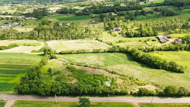 Vista aérea de uma paisagem rural com campos verdes e vegetação densa.