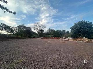 Área externa com terra e vegetação ao fundo.