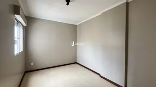 Ambiente interno de uma sala com paredes cinzas e piso de madeira clara.
