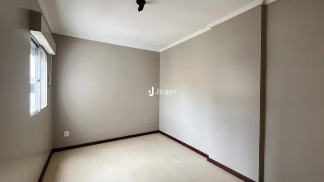 Ambiente interno de uma sala com paredes cinzas e piso de madeira clara.