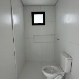 Foto de um banheiro interno com azulejos brancos e um espelho.