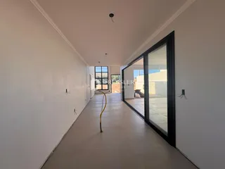 Corredor interno de uma residência com paredes brancas e piso claro.