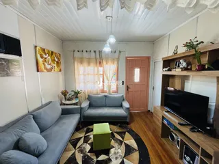 Sala de estar com sofá cinza e piso de madeira no imóvel.