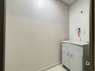 Parede branca de um banheiro com bancada e armário branco.