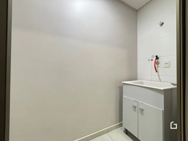 Parede branca de um banheiro com bancada e armário branco.