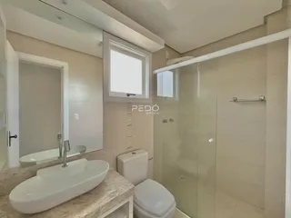 Banheiro moderno com box de vidro e pia de apoio.