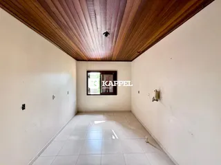 Foto de um corredor interno com paredes brancas e piso de cerâmica.
