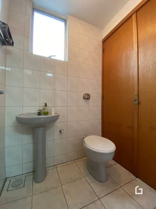 Interior de um banheiro com azulejos brancos e louças sanitárias.