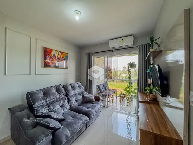 Sala de estar com sofá e porta de vidro abrindo para o exterior.