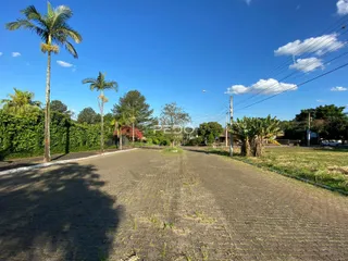 Vista da propriedade com vegetação e estrada sob um céu azul.