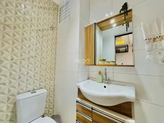 Banheiro com revestimento de parede e pia de cerâmica.
