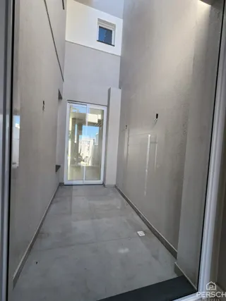 Corredor interno com paredes brancas e piso claro.