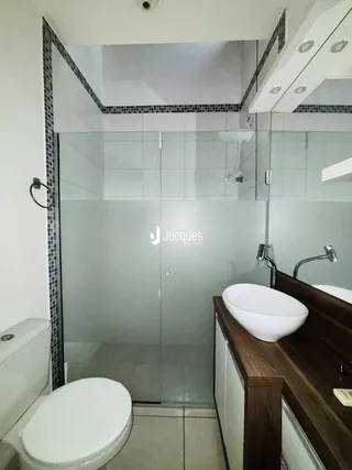 Foto de um banheiro com box de vidro e bancada de madeira.