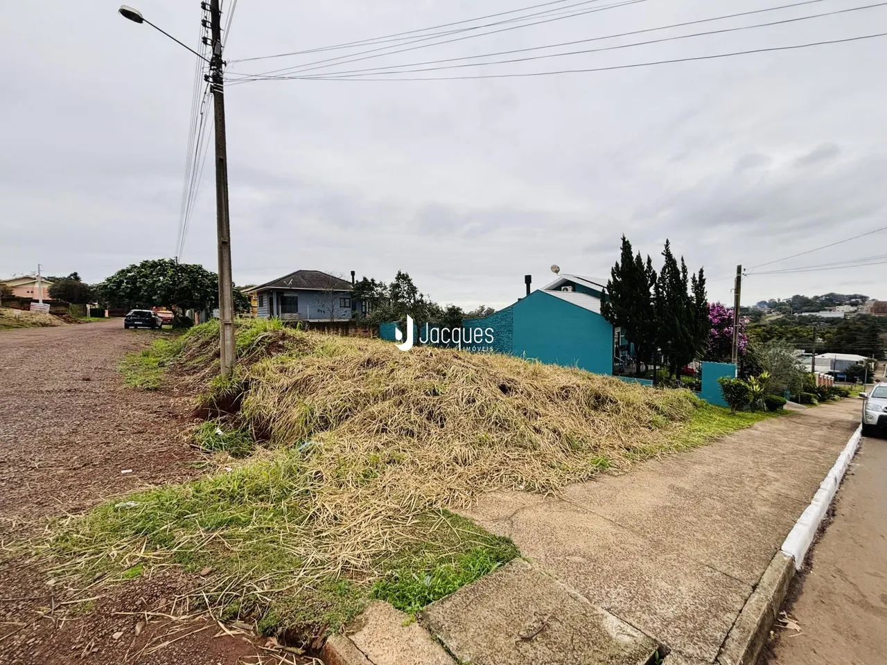 Vista externa de uma propriedade em Lajeado, Brasil, com vegetação na frente e um edifício azul ao fundo.