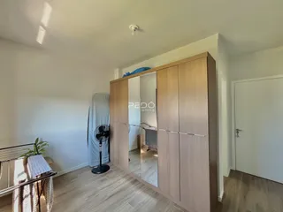 Quarto com guarda-roupa de madeira e piso claro.