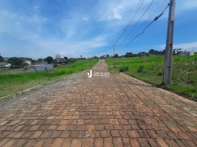 A estrada de paralelepípedos se estende por um campo gramado.