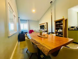 Vista de uma sala de jantar com mesa de madeira no interior de uma residência.