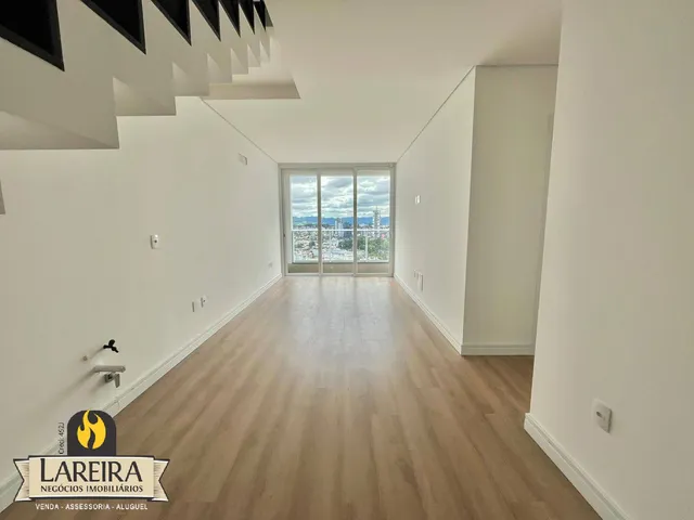 Corredor interno com piso de madeira e vista para a cidade.