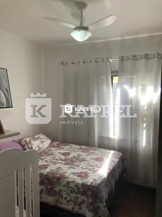 Quarto com cama e cortinas brancas em um imóvel.