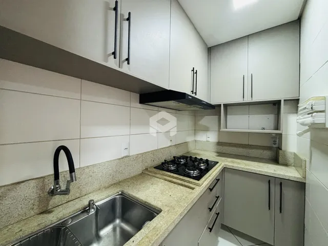 Foto da cozinha com armários brancos e bancada de granito.