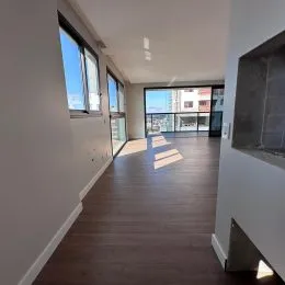 Corredor interno com piso de madeira e janelas em um imóvel em Lajeado.