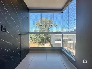 Interior com paredes escuras e piso claro com grande janela de segurança.
