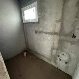 Foto de um cômodo interno com paredes de concreto aparente e uma janela.